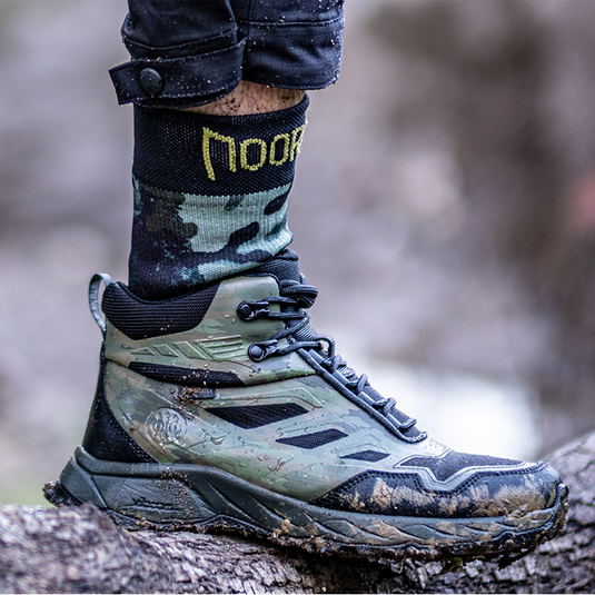 Waterproof socks for hiking in a  wet tactical hiking boot on a tree stump in a natural background