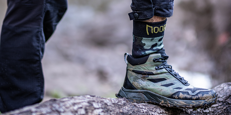Waterproof socks for hiking in a tactical hiking boot on a tree stump in a natural background