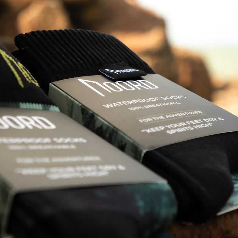 Load image into Gallery viewer, two pairs of waterproof socks with 'Noord' branding on packaging against a blurred natural background
